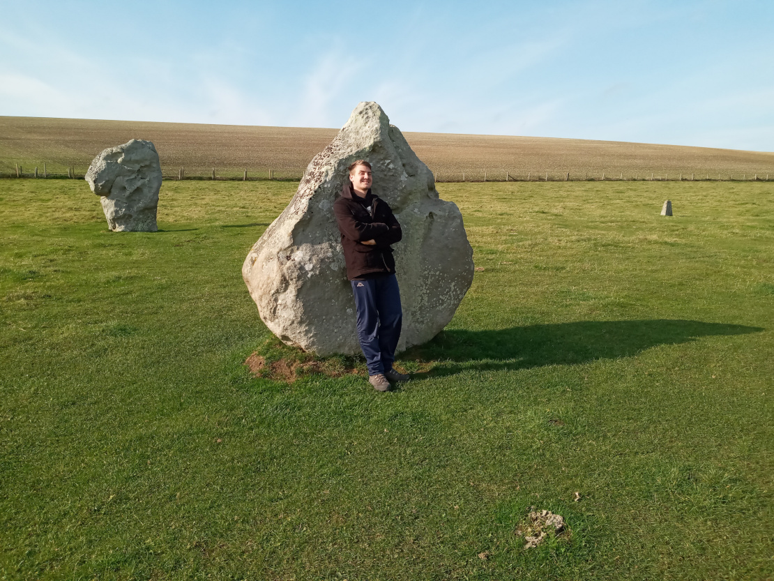Mike leaning against a large stone